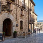 # Hoteles baratos en Segovia: guía completa para dormir bien y gastar poco Segovia es una de las ciudades más bonitas de España y, al mismo tiempo, uno de los destinos donde todavía es posible encontrar hoteles baratos en Segovia en pleno centro histórico, junto al Acueducto o muy cerca del Alcázar. En esta guía encontrarás alojamientos económicos bien valorados, zonas recomendadas para dormir y muchos consejos prácticos para ahorrar sin renunciar a la ubicación ni a la comodidad. A diferencia de otras ciudades turísticas, el precio medio de los hoteles baratos en Segovia sigue siendo razonable fuera de fechas punta (puentes, Semana Santa, Navidad o eventos masivos tipo ‘supersábado’, cuando las noches pueden dispararse a más de 200–250 €). Con algo de planificación y las recomendaciones adecuadas, es fácil encontrar habitaciones dobles cómodas por 30–70 € la noche e incluso apartamentos muy bien ubicados a buen precio. --- ## 1. ¿Qué zona elegir para alojarse en Segovia con presupuesto reducido? Aunque Segovia es compacta, elegir bien la zona marca una gran diferencia en el precio final y en cómo vas a disfrutar tu viaje. Aquí van las áreas clave, con foco en hoteles baratos en Segovia y alojamientos económicos similares. ### 1.1. Casco histórico: la mejor zona… si encuentras chollo Dormir en pleno casco histórico significa estar a pie de: - Plaza Mayor y Catedral - Judería - Alcázar - Calles de tapeo y restaurantes tradicionales En temporada media y baja, hay verdaderas gangas en hoteles baratos en Segovia dentro del centro amurallado. A destacar: - **Hostería Natura** - Ubicación: en plena Plaza Mayor o a escasos metros de ella, según el edificio. - Tipo: hostal con muchísimo encanto. - Lo interesante: habitaciones con paredes de piedra, buena decoración y baño privado; algunas con balcón y vistas a la catedral. - Precio orientativo habitual (fuera de fechas punta): desde unos 30 € / noche en habitación doble, un auténtico chollo para estar en el centro de Segovia. - **Hotel Infanta Isabel by Recordis Hotels** - Ubicación: directamente en la Plaza Mayor, frente a la Catedral. - Categoría: 3 estrellas. - Ventajas: vistas espectaculares, restaurante propio donde probar cochinillo, ambiente clásico. - Perfil: perfecto si quieres un punto más de comodidad pero manteniendo buena relación calidad-precio. - **Hotel Spa La Casa Mudéjar** - Ubicación: edificio del siglo XV junto a la Plaza Mayor. - Categoría: 3 estrellas con spa. - Ideal si: buscas un hotel barato en Segovia *relativamente* (para ser un 3* con spa y ubicación top) y quieres combinar turismo con relax (jacuzzi, sauna, baño turco). En el casco histórico también hay **apartamentos turísticos** con una relación calidad-precio excelente, especialmente si viajas en pareja o en grupo: - **Real Segovia Apartments by Recordis Hotels** - Ubicación: entre el Acueducto y la Plaza Mayor. - Puntuación alta (en torno a 9/10) en Booking por limpieza y trato. - Ideal para: parejas o familias que quieren cocina propia y más espacio. - Desde alrededor de 80–90 € noche para 2 adultos en temporada media, que puede salir muy bien repartido si sois varios. - **Apartamentos Casavillena Turísticos** - Ubicación: a unos 200 metros del Alcázar y de los jardines. - Valoración: fantástica (más de 9/10), muy apreciados por limpieza y ubicación. - Buen equilibrio entre entorno monumental, tranquilidad y precio. **Conclusión de zona**: si encuentras oferta, el casco histórico es la mejor opción para disfrutar de Segovia a pie y aprovechar al máximo los hoteles baratos en Segovia sin gastar en transporte. --- ### 1.2. Zona del Acueducto: dormir junto a la historia El Acueducto romano es uno de los iconos de España y dormir casi debajo de él es un lujo… que no siempre es caro. Esta es otra zona excelente para buscar hoteles baratos en Segovia, con fácil acceso al resto de monumentos en menos de 15–20 minutos andando. Opciones recomendadas: - **Eurostars Plaza Acueducto** - Ubicación: frente al Acueducto, en el casco antiguo. - Categoría: 4 estrellas. - Lo mejor: vistas directas al monumento, diseño moderno y acceso rápido a la catedral y al Alcázar. - Precio habitual fuera de temporada alta: se pueden encontrar noches en el rango 55–70 € si reservas con antelación. - **Hotel Real Segovia** - Ubicación: Plaza de las Sirenas, a medio camino entre el Acueducto y la Catedral. - Categoría: 4 estrellas. - Puntos fuertes: habitaciones luminosas, personal muy amable, ambientación clásica. - Relación calidad-precio: muy buena para estar casi “en medio de todo”. - **Hab Urban Hostel** - Importante: aunque se llame “hostel”, ofrece habitaciones privadas con suelos de parquet, decoración cuidada y muchas con terraza o balcón. - Orientado a: viajeros que buscan alojamiento moderno, bien situado y con precios moderados. Para quien busca hoteles baratos en Segovia con ese plus especial de “me asomo y veo el Acueducto”, esta zona es ideal. --- ### 1.3. La Judería: la zona más romántica La antigua judería de Segovia es un entramado de calles estrechas y empedradas, con pequeñas plazas y casas históricas. Es una de las zonas más románticas y tranquilas para alojarse. Aquí los precios pueden ser algo más altos en hoteles boutique, pero todavía se encuentran **alojamientos económicos**: - **Hospedaje La Judería** - Relación calidad-precio muy buena (habitaciones dobles alrededor de 45 € según temporada). - Decoración cuidada, ambiente íntimo y localización muy céntrica. - **Apartamentos Refitolería** - Apartamentos con 1 o 2 dormitorios, a un paso de la Catedral. - Perfectos para parejas y grupos de hasta 6 personas, con cocina equipada. - Desde unos 75 € por noche el apartamento pequeño, que puede salir muy barato al compartir. En la zona de la Judería también destaca, como ya hemos visto, **La Casa Mudéjar**, muy interesante si quieres sumarle spa a tu escapada. --- ### 1.4. Barrios cercanos: más tranquilidad, mejores precios Si tu prioridad absoluta es el precio, conviene mirar algo fuera del núcleo más turístico. Segovia es muy caminable, y alojarte a 10–15 minutos a pie del centro puede abaratar bastante. Algunas referencias: - **Hotel Apartamentos Aralso (barrio de San Millán)** - Estudios independientes, modernos y muy bien equipados. - A unos 10 minutos caminando del Acueducto y del centro. - Puntuación muy alta (alrededor de 9,4/10) por la atención de los propietarios y la limpieza. - Ideal para estancias de varios días y presupuestos ajustados que no quieren renunciar a la comodidad. - **Aralso Santa Isabel** - Estudios con cocina americana, wifi, lavadora y aparcamiento gratuito. - Muy buena opción para quienes viajan en coche y quieren ahorrar en parking. Estas alternativas, aunque técnicamente no siempre serían los más clásicos “hoteles baratos en Segovia” (muchos son aparthoteles o estudios), compiten en precio con hostales del centro con la ventaja de mayor independencia y cocina propia. --- ### 1.5. Alrededores de Segovia: hoteles rurales y casas a buen precio Si viajas en coche, ampliar el radio de búsqueda a 10–15 km abre opciones muy interesantes, sobre todo en fines de semana largos o cuando la ciudad está casi llena. Ejemplos: - **El Rancho / La Posada del Rancho (Torrecaballeros, a unos 10 km de Segovia)** - Hotel rodeado de campo y montañas, habitaciones amplias y ambiente muy tranquilo. - Habitaciones superiores muy confortables, parking al lado del hotel. - Precios competitivos frente a hoteles de similar categoría en la capital. - **Hotel Rural Costa del Trigo** - Ubicado en un entorno natural tranquilo a unos 29 km de Segovia. - Puntuaciones sobresalientes (en torno al 9,5/10): destaca el trato cercano, la comida casera y el ambiente relajado. - Perfecto si combinas Segovia con rutas rurales y senderismo. - **La Centralita de la Abuela** o **El Torreón de Cepones** - Alojamiento rural con piscina de temporada, jardín y una decoración muy cuidada. - Excelente si buscáis una escapada en grupo o en familia, con más espacio y cocina propia. En muchos casos, estos hoteles rurales salen muy bien de precio, especialmente si viajas en coche y no te importa hacer 10–20 minutos de carretera para visitar la ciudad. --- ## 2. Tipos de alojamientos económicos: hotel, hostal, pensión y apartamento Para encontrar verdaderos hoteles baratos en Segovia conviene entender las diferencias entre los tipos de alojamiento. En España los términos se usan a veces indistintamente, pero no son lo mismo. ### 2.1. Hotel - Habitaciones con baño privado. - Servicios mínimos regulados (recepción, limpieza, etc.), más completos según número de estrellas. - Más variedad de servicios: restaurante, desayuno buffet, gimnasio, spa, parking… - En Segovia, los hoteles de 2 y 3 estrellas pueden ser casi tan baratos como un hostal, con un salto de calidad en instalaciones. Ejemplos de hoteles relativamente económicos: - **Hotel Corregidor** (2 estrellas, cerca del centro histórico) - **Exe Casa de los Linajes** (3 estrellas, muy cerca de puntos clave del casco histórico) - **Hotel Los Arcos** (4 estrellas, a menos de 500 m del Acueducto, con buenas ofertas puntuales) --- ### 2.2. Hostal Según portales especializados y la propia normativa española: - Suelen ser más económicos que los hoteles. - Habitaciones privadas, pero no siempre con baño propio (a veces compartido). - Algún servicio de comidas (cafetería, desayuno sencillo), pero menos instalaciones. En la práctica, para el viajero de presupuesto ajustado, muchos hostales en Segovia ofrecen una relación calidad-precio estupenda: - **Hostal Segovia** (junto al Acueducto, decoración clásica, buena ubicación). - **Hostal Fornos** (a 2 minutos de Plaza Mayor; suelos de parquet, habitaciones agradables a precios muy bajos). Si buscas “hoteles baratos en Segovia”, no limites tu búsqueda solo a hoteles: amplía a hostales y muchas veces encontrarás opciones más baratas y céntricas. --- ### 2.3. Pensión - Término en desuso, pero todavía existen. - Suele ser lo más básico: habitaciones sencillas, trato cercano, instalaciones limitadas. - Suelen ser los alojamientos más económicos, aunque con menos servicios que un hotel o incluso que un hostal. En Segovia muchas antiguas pensiones se han renovado y registrado como hostales u hosterías, por lo que conviene fijarse más en opiniones y fotos que en la etiqueta. --- ### 2.4. Apartamentos y aparthoteles La opción de apartamento ha ganado mucha fuerza: - Más independencia: cocina propia, más espacio, horarios a tu aire. - Muy buena elección para familias y grupos (4–6 personas). - Económico si repartes el coste total entre varias personas y además ahorras en comidas fuera. Ejemplos buenos en Segovia ciudad: - **Real Segovia Apartments** - **Apartamentos Refitolería** - **Hotel Apartamentos Aralso** - **Casavillena Apartamentos Turísticos** En plataformas como Booking, Expedia o Cozycozy puedes filtrar tu búsqueda por tipo de alojamiento y comparar fácilmente con hoteles baratos en Segovia tradicionales. --- ## 3. Plataformas y trucos para encontrar hoteles baratos en Segovia Dado el tamaño y el perfil turístico de la ciudad, conviene comparar en varias webs antes de reservar. Las principales que muestran una buena foto del mercado actual: - **Booking.com** - Muestra listados específicos de *hoteles baratos en Segovia*. - Útil para ver puntuaciones, número de comentarios y ofertas de última hora. - **Expedia** - Sección concreta de alojamientos económicos en Segovia, desde unos 70 €. - Suele combinar bien con vuelos y coche de alquiler si vienes de lejos. - **Kayak, Skyscanner, Trivago, Cozycozy** - Comparadores: te ayudan a ver rápidamente en qué portal sale más barato cada hotel. - Recomendable usar uno o dos antes de reservar para comprobar diferencias de precio. - **Tripadvisor** - Muy útil para leer opiniones detalladas y filtrar por “hoteles baratos” o “hostales y pensiones económicas en Segovia”. ### 3.1. Consejos para encontrar mejor precio 1. **Evita fechas de máxima demanda** - Puentes largos, Semana Santa, fines de semana con eventos (como el famoso ‘supersábado’, cuando muchos hoteles se ponen al 100 % de ocupación y una noche puede llegar a 250 € por pareja). - Si puedes ir entre semana o en temporada baja (otoño, finales de invierno), el mismo hotel puede costar la mitad. 2. **Reserva con antelación, pero mantén flexibilidad** - En Segovia, las mejores ofertas aparecen a menudo varias semanas antes, pero también hay gangas de última hora si la ocupación baja. - Usa cancelación gratuita para “bloquear” un buen precio mientras sigues comparando. 3. **Amplía el mapa** - Considera hoteles en barrios como San Millán o fuera de murallas. - Valora hoteles rurales cercanos si viajas en coche: a menudo son más baratos, más espaciosos y con parking gratuito. 4. **Atento a programas y ofertas especiales** - Algunos hoteles, como el **Hotel Corregidor**, ofrecen programas especiales para mayores de 55 años (tipo IMSERSO) con precios muy bajos por noche en alojamiento y desayuno o media pensión. - Black Friday, promociones de fin de semana o packs románticos a veces dejan hoteles de 4* más baratos que un hostal normal. 5. **Lee siempre las opiniones recientes** - Fíjate especialmente en limpieza, ruidos y calidad de camas. - Un “hotel barato” que no deja dormir o está sucio no compensa, aunque cueste 10 € menos. --- ## 4. Ejemplos de hoteles y alojamientos económicos bien valorados A continuación no es un ranking cerrado, sino una selección orientativa de hoteles baratos en Segovia y alrededores con buena relación calidad-precio según portales como Booking, Cozycozy, Expedia y blogs especializados: ### 4.1. En Segovia capital - **Hostería Natura (Plaza Mayor)** - Tipo: hostal con encanto. - Fortalezas: ubicación inmejorable, precio muy bajo para zona, buenas opiniones. - Perfil: parejas jóvenes, viajeros que priorizan ubicación céntrica y ahorro. - **Hotel Corregidor (2*)** - Ubicación: distrito histórico, a 500 m del Acueducto. - Fortalezas: vistas, bar, parking, programas de precios especiales. - Excelente opción como “hotel barato en Segovia” clásico. - **Hotel Eurostars Plaza Acueducto (4*)** - Ubicación: junto al Acueducto. - Fortalezas: vistas monumentales, diseño moderno, buena relación calidad-precio, sobre todo fuera de temporada alta. - **Exe Casa de los Linajes (3*)** - Ubicación: muy céntrica, cerca de la Casa-Museo de Antonio Machado y del Palacio Episcopal. - Extras: gimnasio, terraza con vistas, salas de conferencias, opciones sin contacto para check-in/out. - Buena combinación de precio, ubicación y servicios. - **Hotel Spa La Casa Mudéjar (3*)** - Ubicación: calle principal muy cerca de Plaza Mayor. - Fortalezas: edificio histórico del siglo XV, spa, dos restaurantes (cocina castellana y sefardí). - Interesante para escapada de relax económica comparada con otros spa urbanos. - **Real Segovia By Recordis Hotels (4*)** - Ubicación: Plaza de las Sirenas, corazón de la ciudad. - Fortalezas: limpieza, decoración clásica, servicios como piscina, jacuzzi, terraza y spa (según temporada y tipo de reserva). - **Hotel Los Arcos (4*)** - Ubicación: menos de 500 m del Acueducto. - Fortalezas: restaurante reconocido por guías gastronómicas, parking, ubicación práctica. ### 4.2. Alrededores rurales y otros municipios cercanos - **Hotel Cándido (4* sup.)** - Ubicación: zona tranquila a unos 7 km del Acueducto. - Servicios: spa (con horarios y cierres específicos), piscina, gimnasio, restaurante de cocina segoviana (incluye cochinillo), aparcamiento. - Muy buena relación calidad-precio si valoras instalaciones de categoría y te mueves en coche. - **Parador de Segovia (4*)** - Ubicación: a las afueras, con vistas panorámicas de la ciudad. - Servicios: piscina climatizada, jardín, restaurante, salas para eventos. - No es el más barato, pero puede resultar competitivo en determinadas fechas frente a 4* del casco histórico. - **Parador de La Granja (4*)** – La Granja de San Ildefonso - Ubicación: localidad monumental a 10–15 km de Segovia, entorno palaciego y naturaleza. - Interesante si: combinas visita a Segovia ciudad con la Granja de San Ildefonso y buscas un entorno más tranquilo. - **Hoteles rurales como La Posada del Rancho, Costa del Trigo, La Centralita de la Abuela, El Torreón de Cepones** - Perfiles: escapadas rurales, grupos, familias, amantes de la naturaleza. - Ventaja clara: mucho espacio, entornos naturales bonitos, buena relación m²/precio. --- ## 5. Cuándo es más barato viajar a Segovia El clima y el calendario turístico influyen directamente en el precio de los hoteles baratos en Segovia: - **Meses más cálidos**: julio y agosto, con temperatura media alrededor de 20 °C. - **Meses más fríos**: enero y febrero, con medias en torno a 4 °C. - **Precipitación anual**: unos 600 mm repartidos sobre todo en otoño y primavera. ### Temporadas recomendadas para ahorrar - **Finales de otoño (noviembre)** y **finales de invierno (febrero)** - Menos turismo masivo, más ofertas hoteleras. - Ciudad mucho más tranquila. - **Entre semana (de lunes a jueves)** - Los fines de semana, puentes y fiestas especiales suelen disparar los precios. - Si tu agenda te lo permite, dos noches entre semana pueden costar lo mismo que una en sábado en temporada alta. ### Fechas a evitar si buscas precios mínimos - Semana Santa - Puentes nacionales y autonómicos - Fines de semana con eventos importantes (deportivos, culturales, congresos), como el mencionado ‘supersábado’, cuando la prensa local ha llegado a informar de medias de 250 € por pareja y noche en la capital. --- ## 6. Cómo moverse por Segovia de forma económica Una vez asegurado el alojamiento, conviene controlar también los gastos en transporte: - **Llegar en tren** - Estaciones: - Segovia (cercana al casco urbano). - Segovia Guiomar (AVE, algo más alejada, conectada por bus o taxi). - Si te alojas en el centro, no necesitarás coche para moverte. - **A pie** - Ciudad muy cómoda para recorrer andando: del Acueducto al Alcázar hay unos 20 minutos de paseo atravesando todo el centro. - Si eliges bien el alojamiento, podrás visitar prácticamente todo sin transporte adicional. - **Autobús urbano / taxi** - Interesante si te alojas un poco más lejos (barrios nuevos, hoteles periféricos, estación AVE) y quieres bajar al centro sin mover coche. - **Coche** - Ventaja: más libertad para alojarte en hoteles rurales baratos, visitar La Granja, pueblos cercanos, etc. - Inconveniente: aparcar en el centro histórico es difícil y de pago (ORA, parkings públicos). - Consejo: si vienes en coche, valora muy bien hoteles con parking incluido (Cándido, algunos 4* y rurales) o zona gratuita cercana. --- ## 7. Consejos finales para encontrar hoteles baratos en Segovia y acertar 1. **Prioriza ubicación + limpieza** - En una ciudad como Segovia, poder volver andando al hotel tras cenar o tomar algo es un plus enorme. - Un hotel barato en Segovia a 15 minutos del centro a pie suele compensar frente a uno más alejado sin esa posibilidad. 2. **Hostal céntrico vs hotel 4* más lejano** - Muchas veces un hostal u hostería en pleno casco histórico (Natura, Segovia, Fornos) ofrece mejor experiencia global que un 4* alejado si tu plan es turismo urbano. - Valora lo que más te interesa: servicios extra (spa, piscina, gimnasio) o vivir la ciudad desde dentro. 3. **Si viajas en grupo, piensa en apartamentos** - Un apartamento para 4–6 personas a 80–100 € la noche (Real Segovia Apartments, Refitolería, Casavillena, Aralso) puede ser mucho más barato que 2–3 habitaciones en hotel, y encima dispondrás de cocina. 4. **No te obsesiones con las estrellas** - Hay 2* o 3* en Segovia con mejores opiniones que algunos 4*. - Mira fotos, comentarios recientes, año de la última reforma y servicios que realmente vas a usar. 5. **Reserva con cancelación gratuita cuando haya previsión de subidas** - Ante eventos grandes o periodos muy demandados, asegurar un buen precio con cancelación gratuita es una buena estrategia para hoteles baratos en Segovia, evitando subidas de última hora. --- ## Preguntas frecuentes sobre hoteles baratos en Segovia ### ¿Es fácil encontrar hoteles baratos en Segovia en pleno centro? Sí, especialmente fuera de fechas punta. Hostales como Hostería Natura, Hostal Fornos o Hostal Segovia permiten dormir a pocos metros de la Plaza Mayor o del Acueducto por 30–45 € la noche en habitación doble según temporada. También hay hoteles de 2–3 estrellas con muy buenas ofertas. ### ¿Qué es más barato en Segovia, hotel o hostal? En general, los **hostales** suelen ser más económicos que los hoteles, y muchas veces ofrecen una relación calidad-precio extraordinaria (habitaciones privadas, buenas ubicaciones, ambiente familiar). Sin embargo, en determinadas promociones, algunos **hoteles de 3–4 estrellas** pueden estar igual o incluso más baratos que un hostal modesto. Lo ideal es comparar siempre. ### ¿Dónde están los mejores hoteles baratos en Segovia para ir a pie a todos los monumentos? Las mejores zonas son: - **Casco histórico (Plaza Mayor, Judería, barrio de San Esteban)** - **Entorno del Acueducto** Desde cualquiera de estas áreas llegarás caminando en minutos al Alcázar, la Catedral y las principales calles de tapas y restaurantes. ### ¿Es buena idea alojarse en un pueblo cercano para ahorrar? Si viajas en coche, sí. Hoteles rurales en Torrecaballeros, La Granja o pequeñas localidades a 10–20 km suelen ofrecer precios muy competitivos, más espacio, parking gratuito y entornos más tranquilos. Solo debes tener en cuenta el tiempo de desplazamiento diario hasta la ciudad. ### ¿Qué rango de precios es razonable para hoteles baratos en Segovia? Fuera de grandes eventos, es razonable encontrar: - Hostales y pensiones céntricas: **30–45 € / noche** en doble. - Hoteles 2–3 estrellas en la ciudad: **45–80 € / noche**. - Hoteles 4 estrellas con ofertas: **60–110 € / noche**, según temporada y antelación. - Apartamentos bien ubicados: desde **55–100 € / noche**, muy convenientes si compartes gastos. ### ¿Cuándo suben más los precios de los hoteles en Segovia? - Semana Santa - Verano (especialmente fines de semana) - Puentes y festivos - Fines de semana con eventos deportivos, culturales o congresos (como el ‘supersábado’), cuando la ocupación alcanza el 100 % y los precios por noche pueden superar ampliamente los 200 € por pareja. ### ¿Qué plataformas son más útiles para encontrar hoteles baratos en Segovia? Las más prácticas para comparar y reservar son: - **Booking.com** (mucha oferta y filtros específicos para “económicos”) - **Expedia** (buenas combinaciones con otros servicios) - **Kayak, Skyscanner, Trivago, Cozycozy** (comparadores de precio) - **Tripadvisor** (opiniones y listas de hoteles baratos en Segovia y hostales económicos) --- En resumen, elegir bien la zona, comparar tipos de alojamiento (hotel, hostal, apartamento) y reservar con algo de antelación son las claves para disfrutar de hoteles baratos en Segovia sin renunciar a una buena ubicación ni a la comodidad. Con esta guía, ya tienes una base sólida para encontrar el alojamiento que mejor encaje con tu presupuesto y tu estilo de viaje.