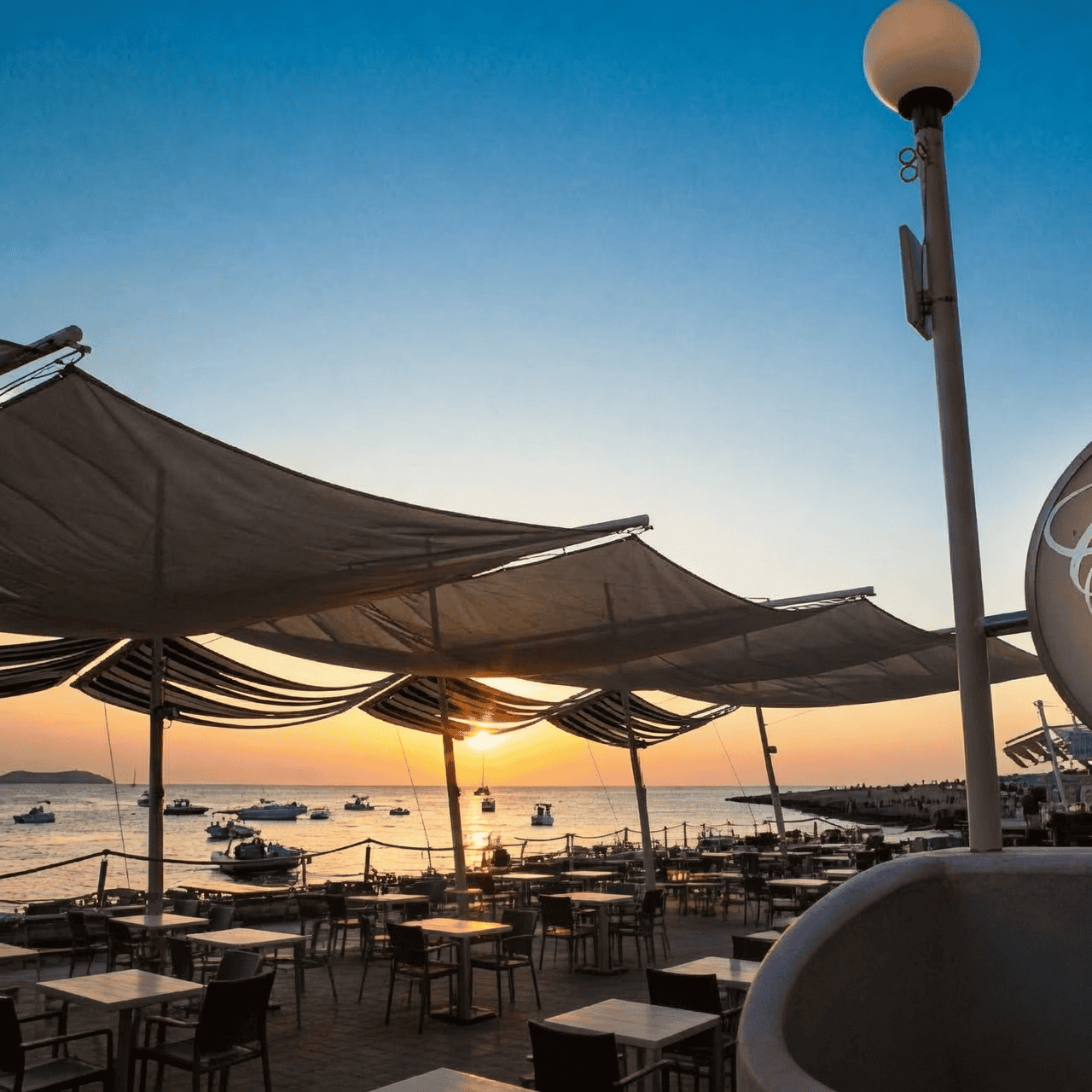 Terraza de un bar frente al mar al atardecer en Sant Antoni, Ibiza