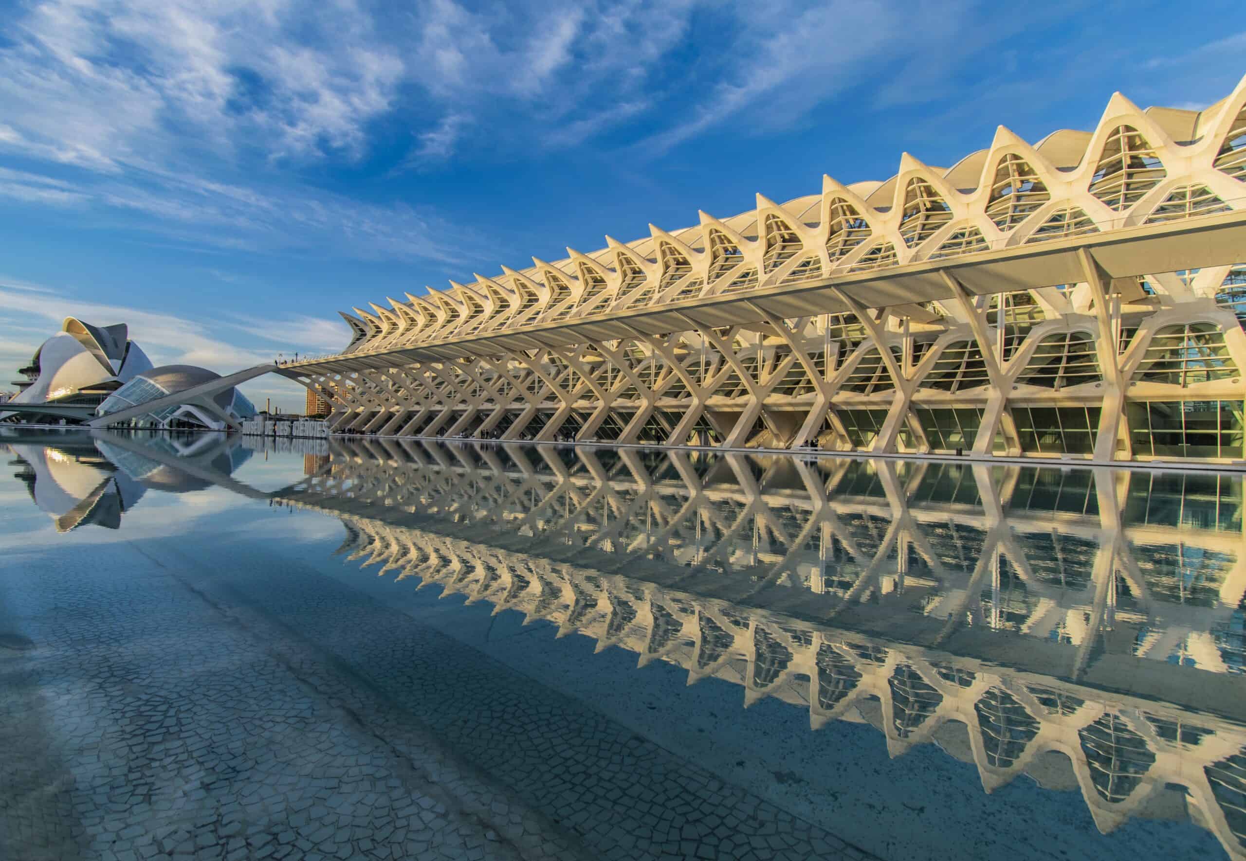 Ciudad de las Artes y las Ciencias de Valencia al atardecer, con los edificios iluminados reflejándose en los estanques del complejo