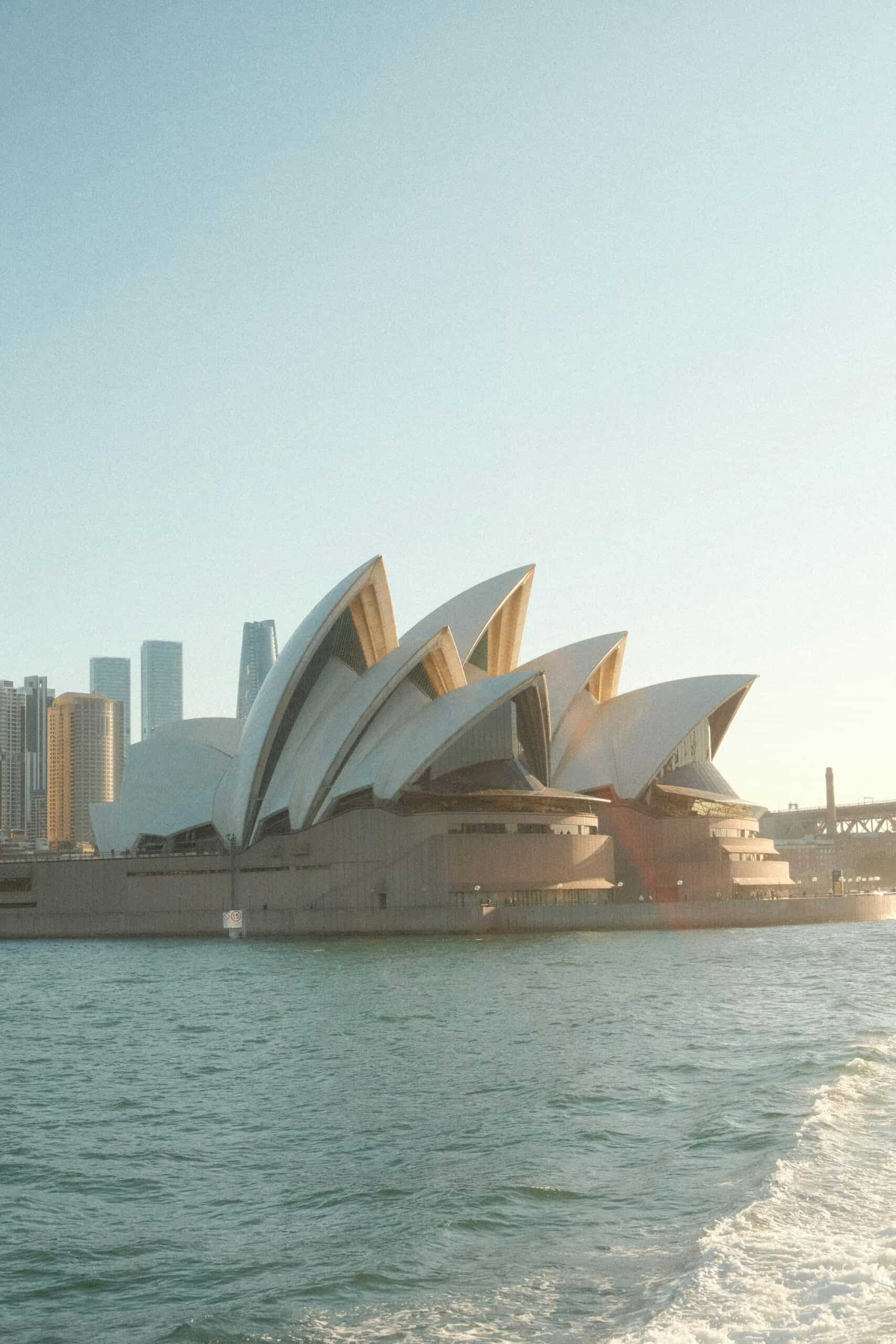 Ópera de Sídney vista desde la bahía con el Sydney Harbour Bridge al fondo