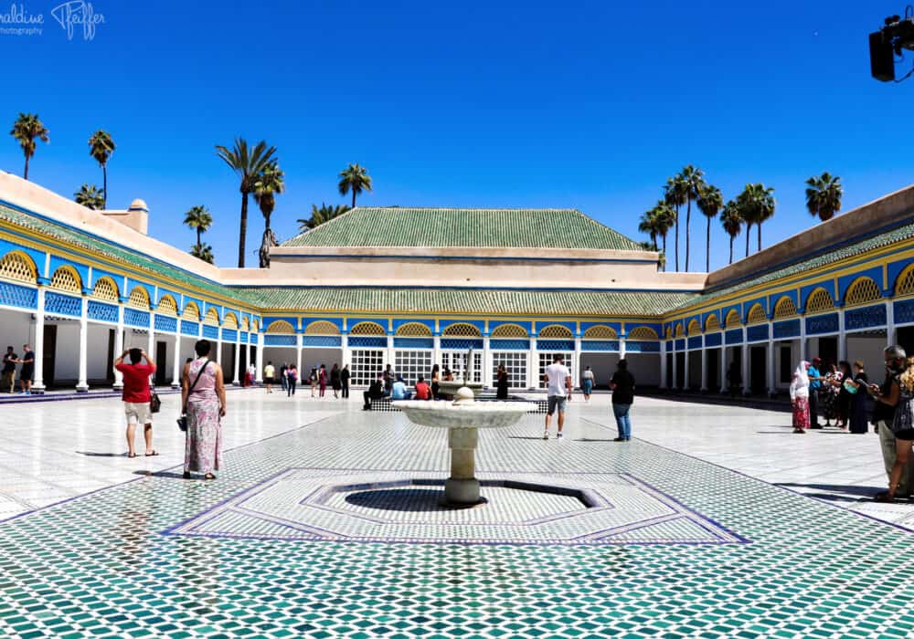 Patio del Palacio de la Bahía con fuente y visitantes en Marrakech.
