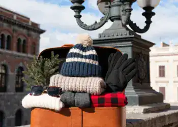 Maleta abierta con ropa de invierno junto a farola